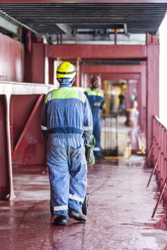 Crew member seen from behind carrying out daily deck operations while the vessel is underway, focus and responsibility in a maritime environment.