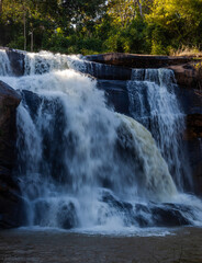 Tat Huang Waterfall cascading through rocks in Phu Suan Sai National Park, Thailand. Lush greenery surrounds the flowing water. Tropical forest landscape with scenic water streams.