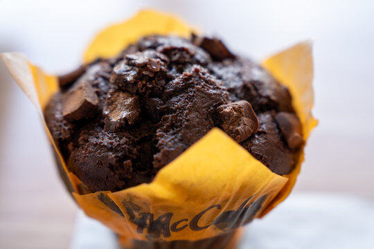 Belgrade, Serbia: July 3, 2024: close up of a chocolate mccafe muffin topped with chunky chocolate pieces in a yellow and brown paper wrapper 