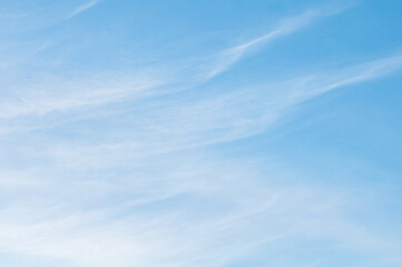 Soft wispy cirrus clouds stretching across a clear blue sky creating a calm minimalist nature background with gentle textures and copy space © kunal