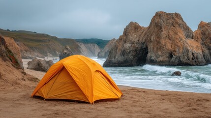 Vibrant orange tent pitched on sandy beach with rugged rock formations near the ocean under overcast sky