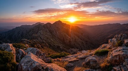 Naklejka premium Majestic Sunset Over Rugged Mountain Range With Vibrant Sky and Glowing Sunlight Illuminating Rocky Landscape