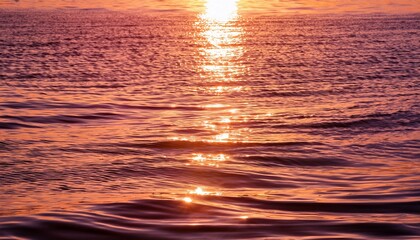 water surface with gentle waves reflecting soft hues of orange and pink from the sunlight creating a tranquil and shimmering effect