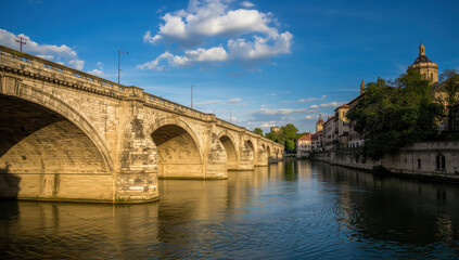 Obraz premium Stone bridge riverbank historic bridge arch reflection blue sky warm light