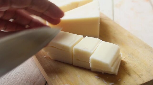 slicing cheese with a knife on a cutting board