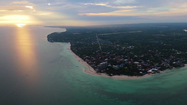 A breathtaking aerial drone shot of Bantayan Island at sunset, showing the golden sun reflecting on the calm sea and the tropical coastline of the Philippines