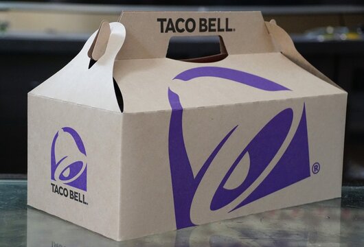Wilmington, Delaware, U.S.A - Feb 21, 2026 - A Taco Bell takeout box featuring the company's signature purple design and handle for carrying multiple food items