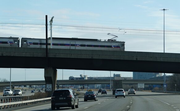 Essington, Pennsylvania, U.S - Feb 21, 2026 - SEPTA commuter train travels on an elevated track above a busy highway with vehicles moving beneath near Philadelphia International Airport
