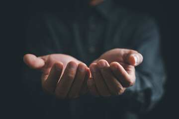 Obraz premium Close-up of cupped hands with fingers outstretched against a dark background.