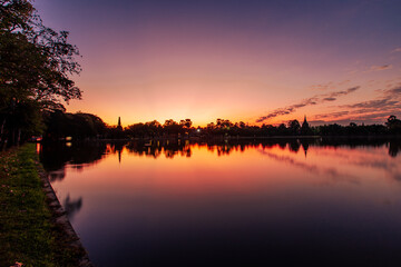 Obraz premium Blurred nature background of the morning sun by the sea, a beautiful golden light, among the trees, rocks and local fishing boats, the beauty of nature during the day.