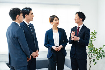 オフィスで会話する日本人ビジネスチームのミーティング風景