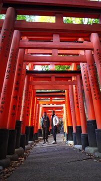 Two travelers walking through the iconic torii gates of Fushimi Inari Taisha, Kyoto, Japan