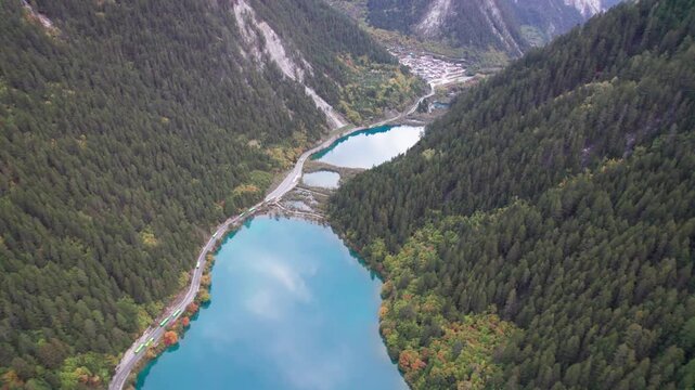 Drone view of Jiuzhaigou National Park in autumn in Sichuan Province China. It features cascading waterfalls, turquoise blue lakes, and stunning mountain valleys. 4K real time footage travel concept