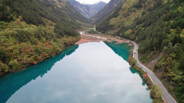 Drone view of Jiuzhaigou National Park in autumn in Sichuan Province China. It features cascading waterfalls, turquoise blue lakes, and stunning mountain valleys. 4K real time footage travel concept