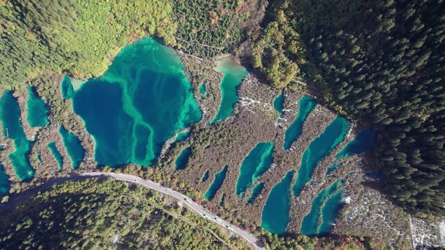 Drone view of Jiuzhaigou National Park in autumn in Sichuan Province China. It features cascading waterfalls, turquoise blue lakes, and stunning mountain valleys. 4K real time footage travel concept