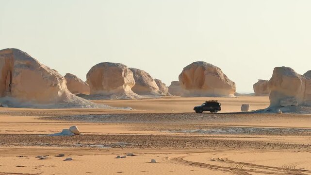 4x4 jeep driving fast across sandy desert plain among rock formations