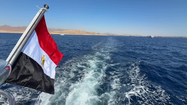 Close up of Egyptian national flag waving in the wind on the upper yacht deck with deep Red sea water in the background