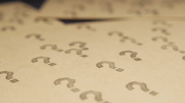 Abstract close up macro motion video of multiple question marks printed on paper creating a pattern and texture concept