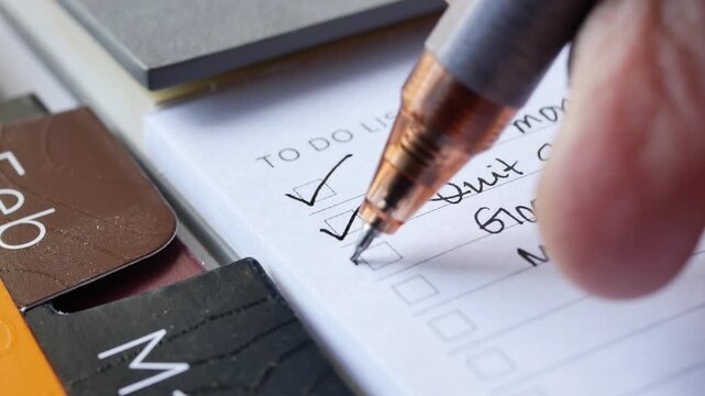 Close up video footage of person checking off items on a to-do list with a pen, signifying task completion and productivity