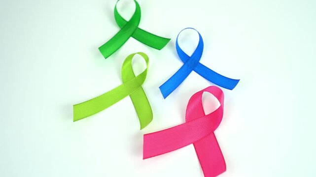 Four colorful ribbons, lime green, green, blue, and pink, isolated on white background. symbolizes awareness and support for cancer 