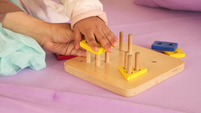 Toddler plays with colorful wooden shape sorter toy, learning and developing motor skills