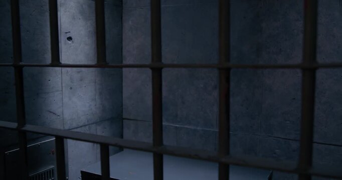 Wide shot of empty prison cell with dramatic lighting as the camera slowly pans right.