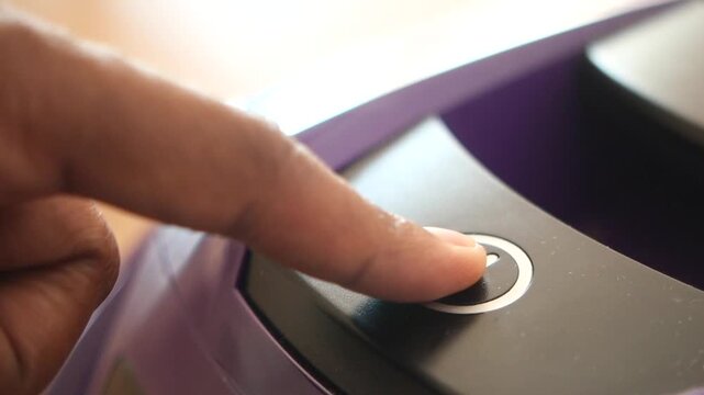 Close-up cinematic shot of human finger pressing on power button on electronic device, activating functions with precision