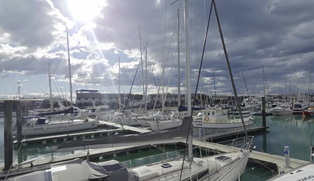 Wide-angle view of a marina with sailboats under a dramatic cloudy sky