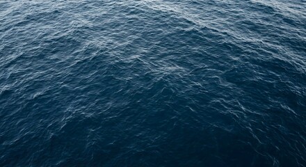 Deep blue ocean water surface with rippled texture and soft daylight. Calm sea waves in a high-angle view outdoors. Serene aquatic background for summer vacation and marine nature concept.