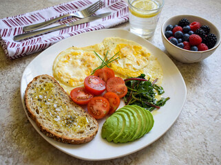Healthy breakfast fried eggs with avocado, tomatoes and whole grain toast