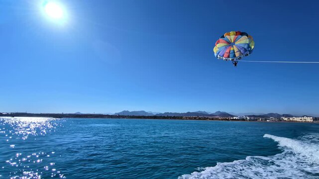 A parasailor is lifted high above the shimmering blue waters near Sharm El Sheikh, Egypt