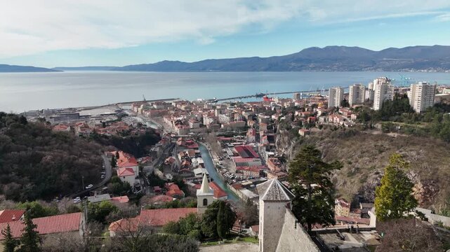 Drone descends near Trsat Castle, revealing the Rječina valley and the Adriatic Sea in a wide aerial view as it lands near the hilltop fortress.