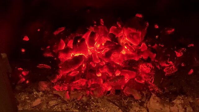 Hot charcoal burning inside a fireplace or barbecue, providing heat and a luminous effect in the dark
