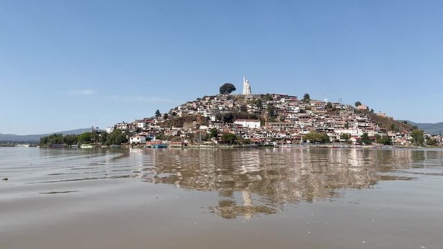 Serene view of Janitzio Island reflecting on a tranquil lake under blue skies