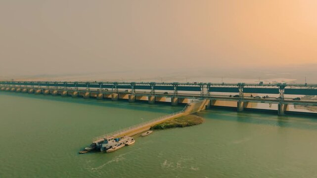 Kotri Barrage, a large dam structure, regulating water flow in the Indus River under a vast sky at sunset