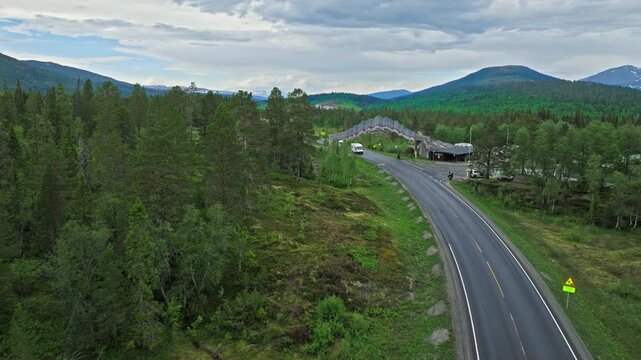 Aerial drone view of Tr&oslash;ndelag border station and highway in Norway. Norwegian road curves past forested hills and small buildings near the regional boundary.