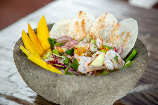 Mexican shrimp dish served with mango and tortillas in a stone bowl.