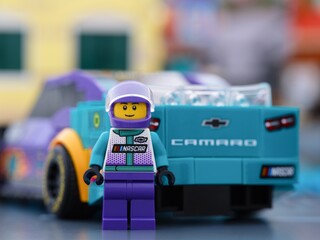 Fototapeta premium Tambov, Russian Federation - January 02, 2026 Lego NASCAR Next Gen Chevrolet Camaro ZL1 driver minifigure standing near back of his car. LEGO Speed Champions.