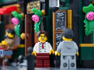 Fototapeta premium Tambov, Russian Federation - June 24, 2025 Lego waiter and customer minifigures standing outdoors near a cafe.