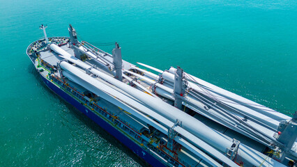 Large heavy lift cargo ship transporting massive wind turbine blades across the deep blue ocean. Global logistics for renewable energy and maritime shipping industry business concept. © Yellow Boat