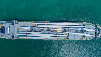 Large heavy lift cargo ship transporting massive wind turbine blades across the deep blue ocean. Global logistics for renewable energy and maritime shipping industry business concept. © Yellow Boat