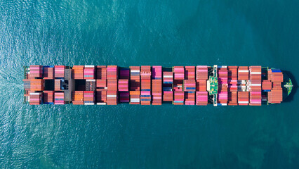 Massive container ship fully loaded with colorful freight sailing across the deep blue ocean....