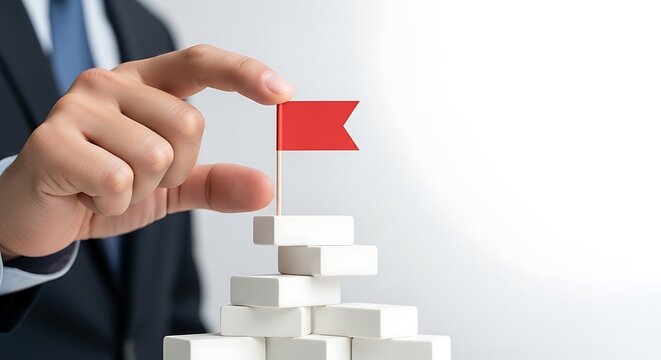 Businessman placing red flag on top of white blocks, business success concept.