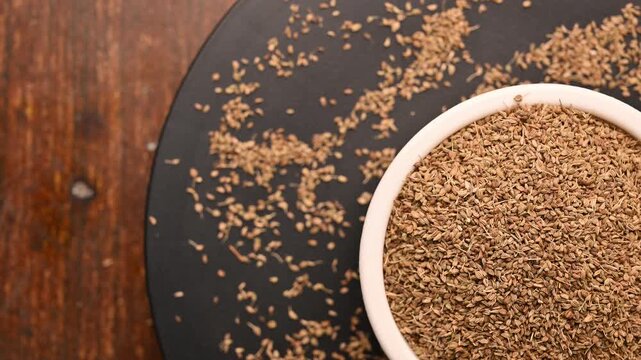 Top View of Carom Seeds (Ajwain) in White Bowl on Black Background &ndash; Rotating Footage