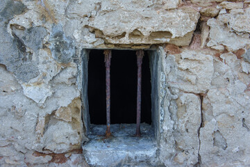 Old stone prison window with rusty bars in a historic building.