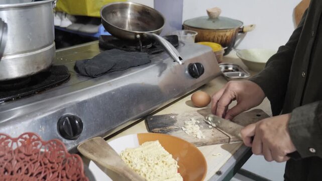 Close up of anonymous woman hands chopping and mincing fresh garlic cloves on a wooden cutting board