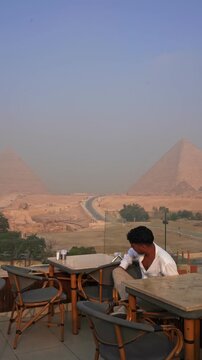 Traveler overlooking the Great Pyramids of Giza from a rooftop caf&eacute;, Egypt