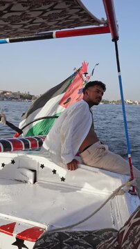 Traveler relaxing on a traditional felucca sailing on the Nile River, Egypt