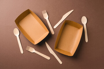 Fototapeta premium Minimal wooden cutlery set in kraft tray on brown background
