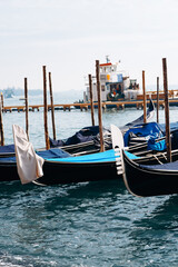 Fototapeta premium Boats sit in water near a dock as a boat arrives in the distance